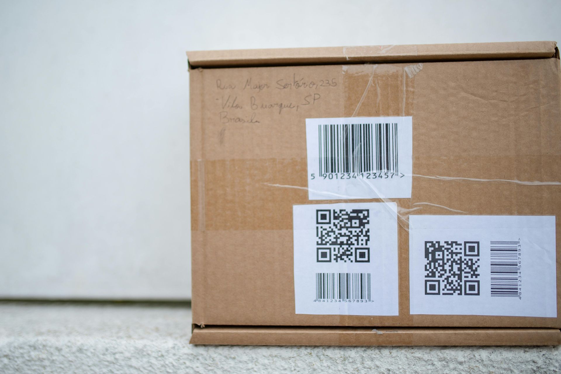 Cardboard box with shipping labels and handwritten address.