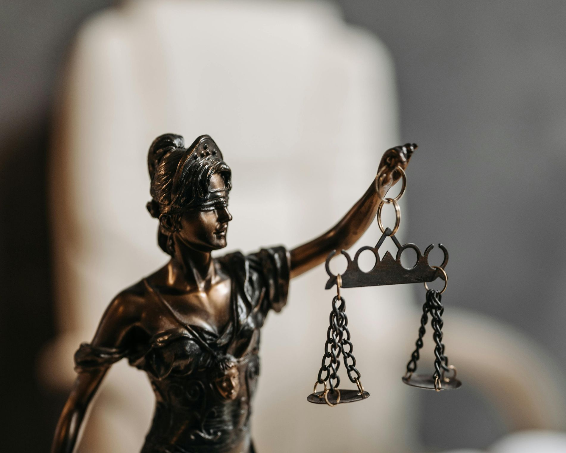 Statue of Lady Justice holding scales and sword. Bronze color on a desk.