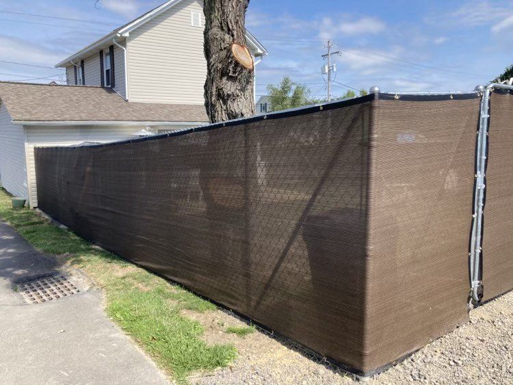 Brown privacy fence alongside a house with a tree trunk in the middle.