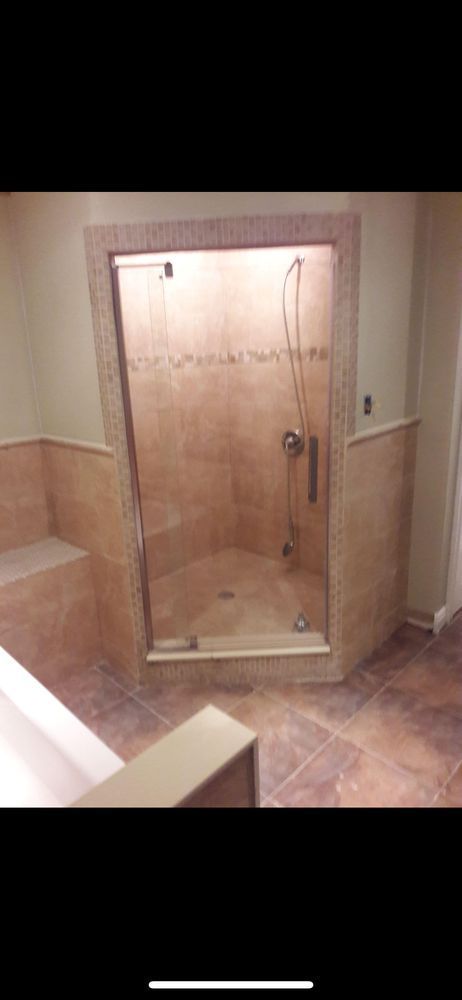 A bathroom with a clear glass shower door. The walls are tiled in brown stone.