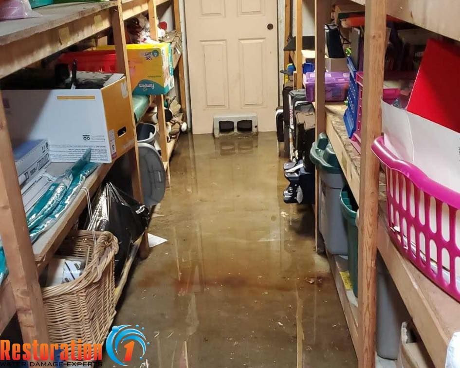 Flooded storage room with wooden shelves on both sides of a hallway leading to a closed door.