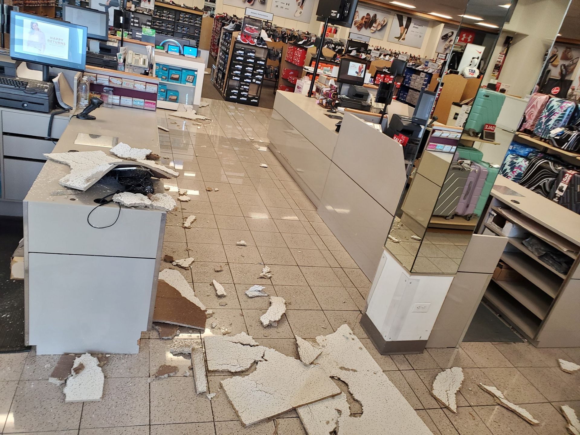 Debris from a collapsed ceiling litters the floor of a retail store behind a service counter and checkout area.