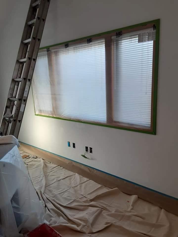 A room with a ladder and a window being painted.