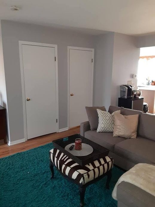 A living room with a couch , coffee table , and zebra print ottoman.