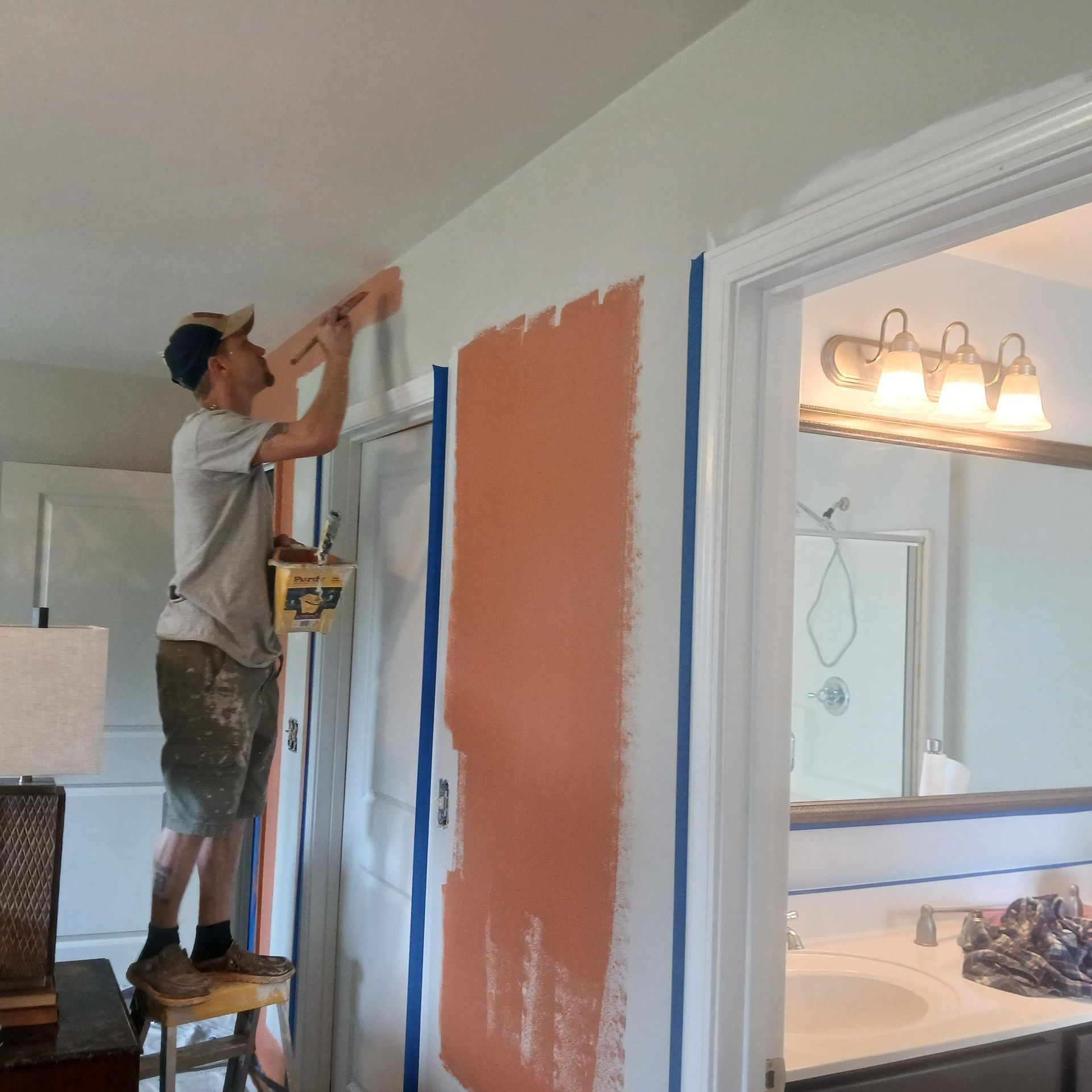 A man is painting a wall in a bathroom