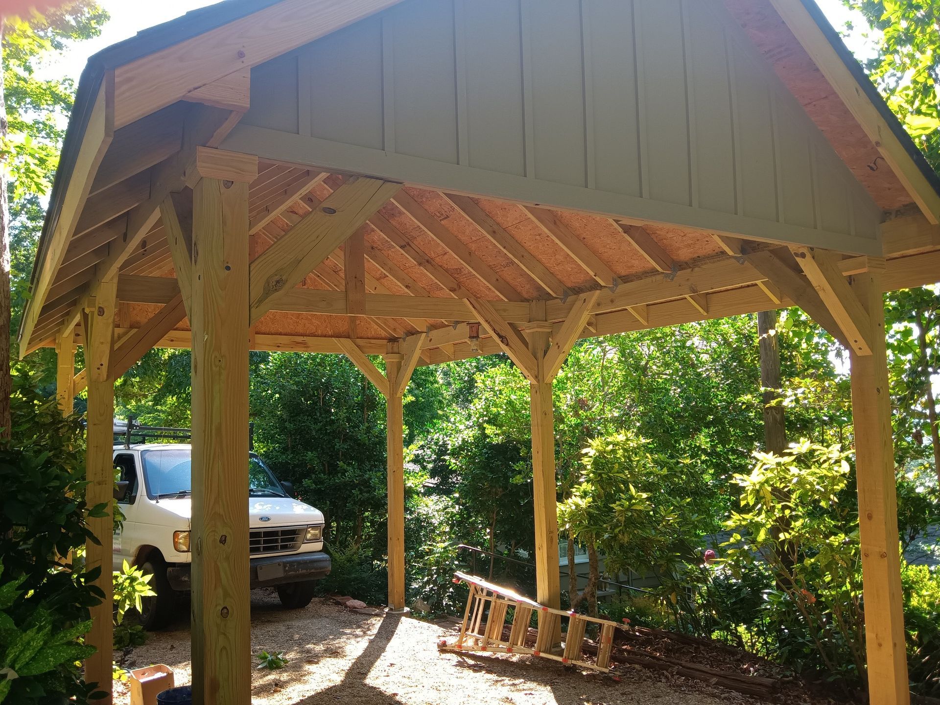 A white van is parked under a wooden structure