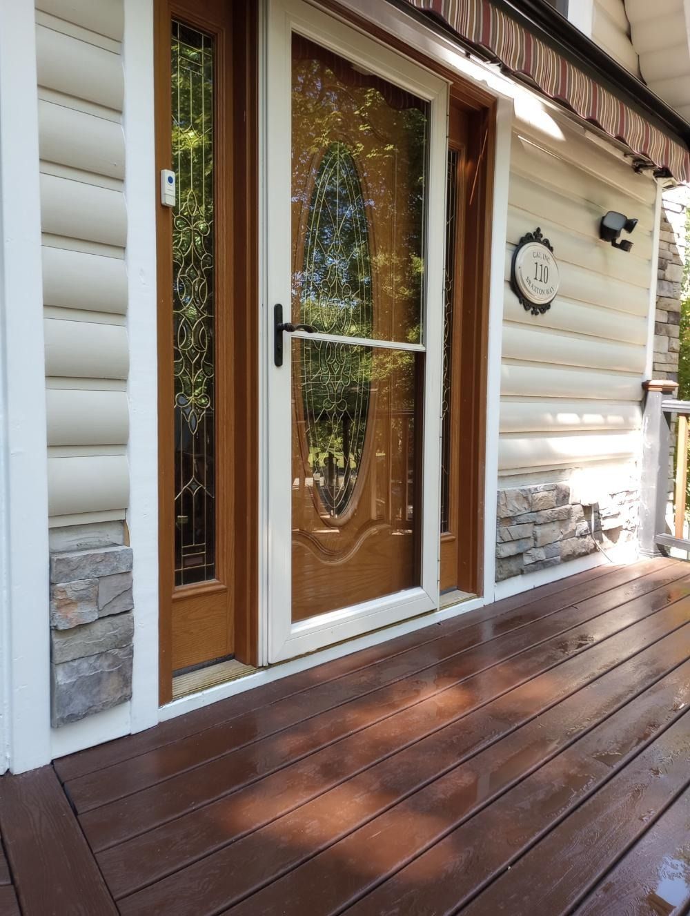 The front door of a log cabin with a wooden deck in front of it.