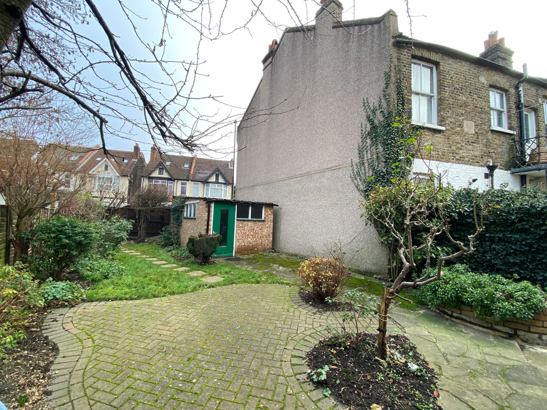 A backyard with a brick walkway leading to a house.