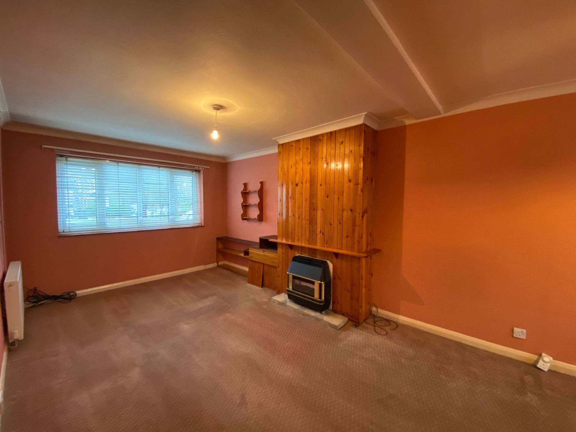 An empty living room with pink walls and a fireplace.