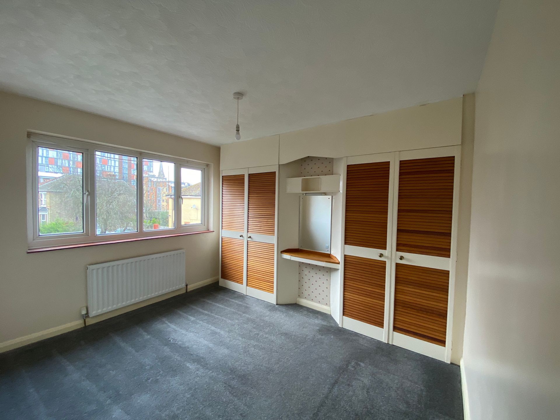 An empty room with a lot of cabinets and a window.
