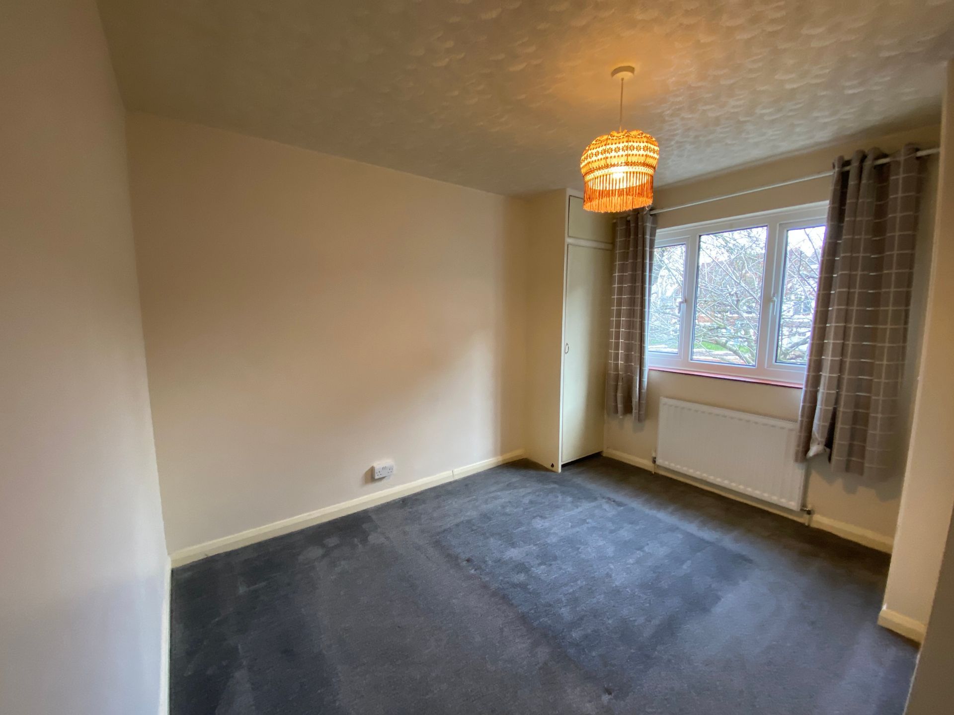 An empty bedroom with a carpeted floor and a window.