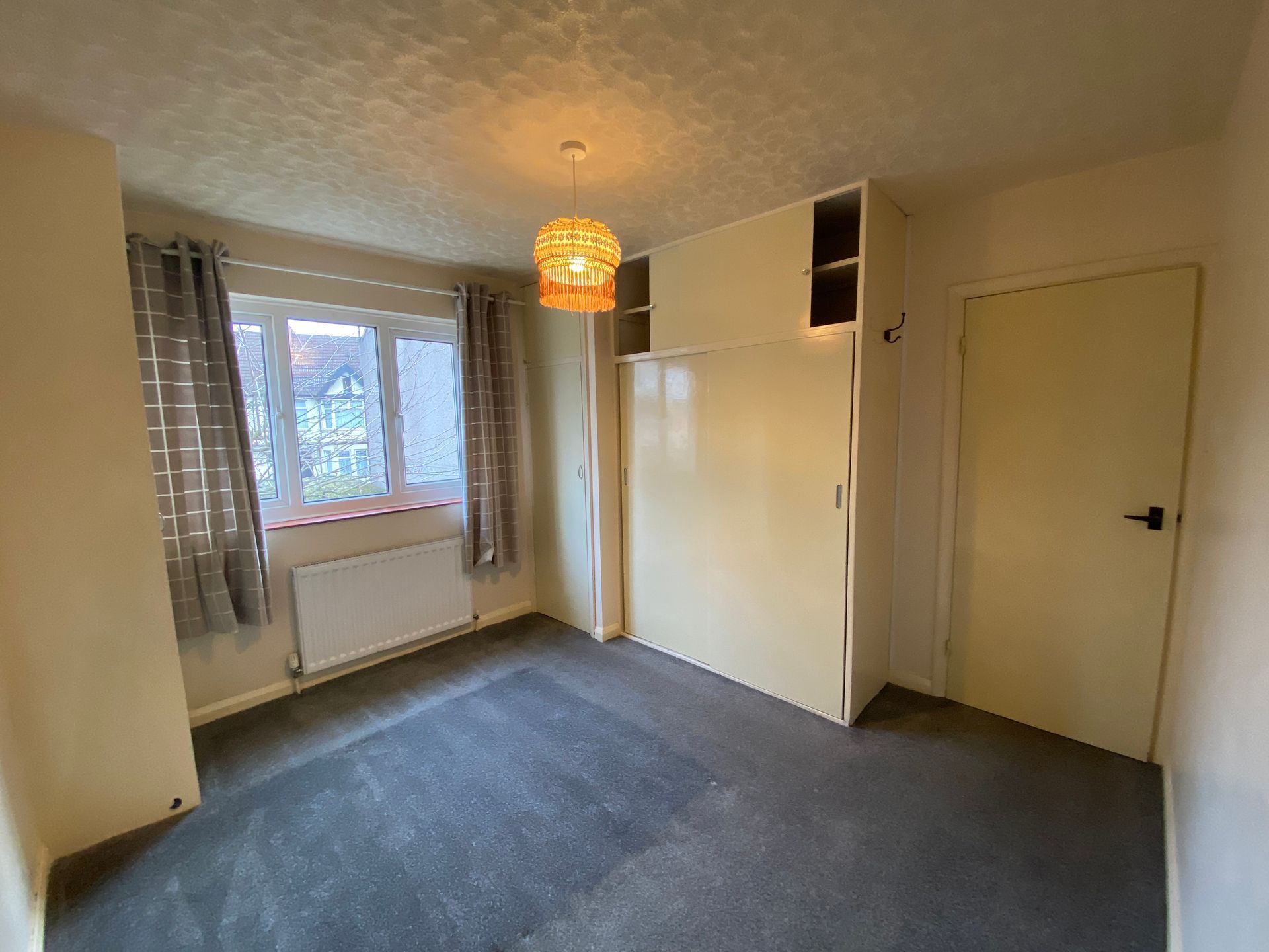 An empty bedroom with a carpeted floor and a window.
