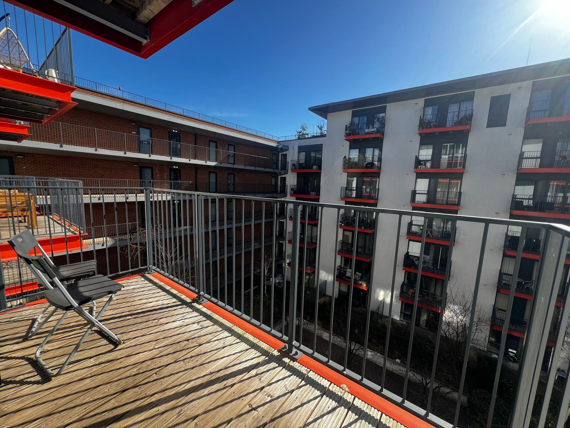 A balcony with a chair and a table in front of a building.