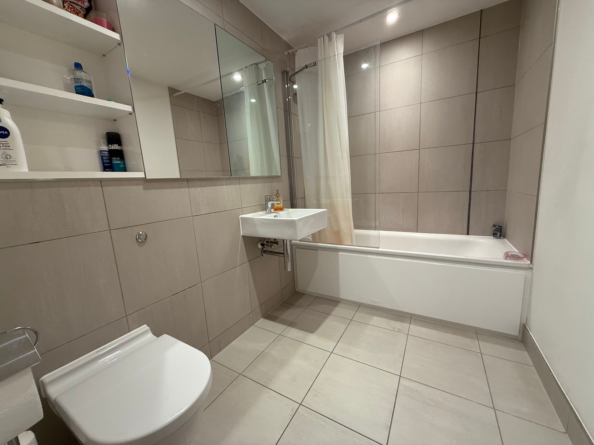 A bathroom with a toilet , sink and bathtub.