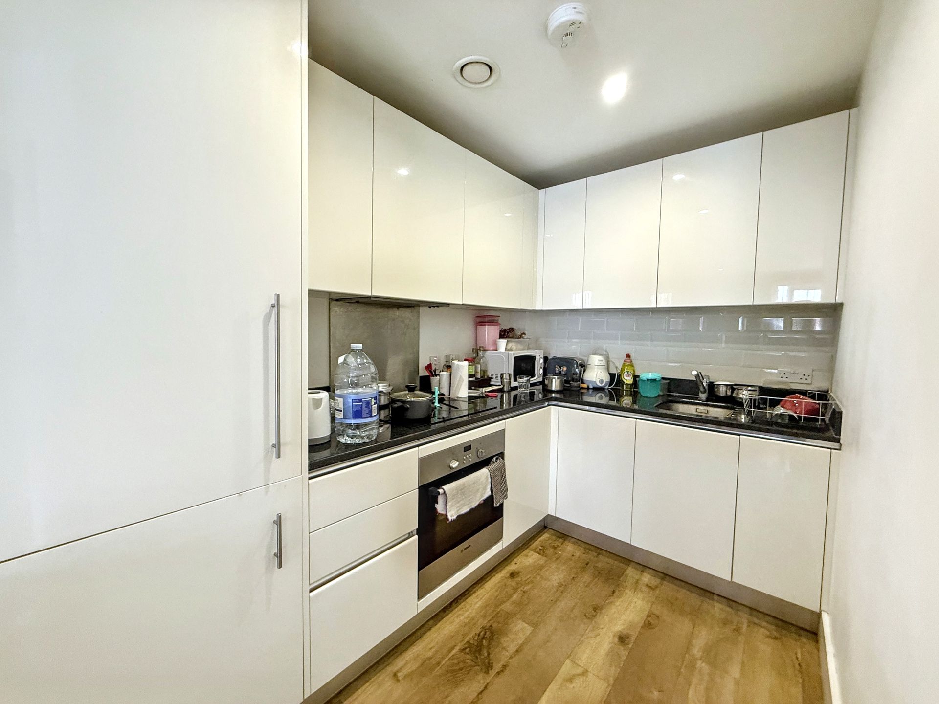 A kitchen with white cabinets , stainless steel appliances , and wooden floors.