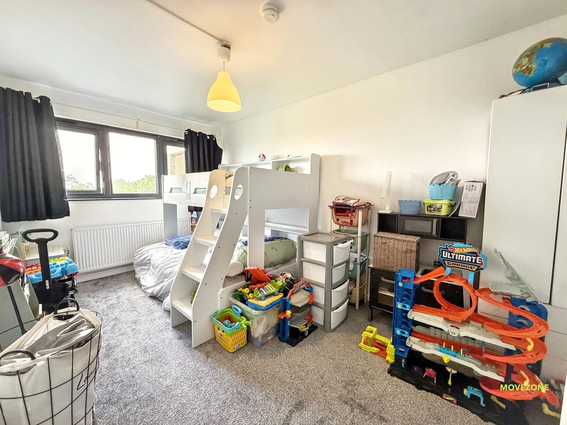 Children's bedroom with bunk bed, toys, storage bins, and a toy garage on a gray carpet.