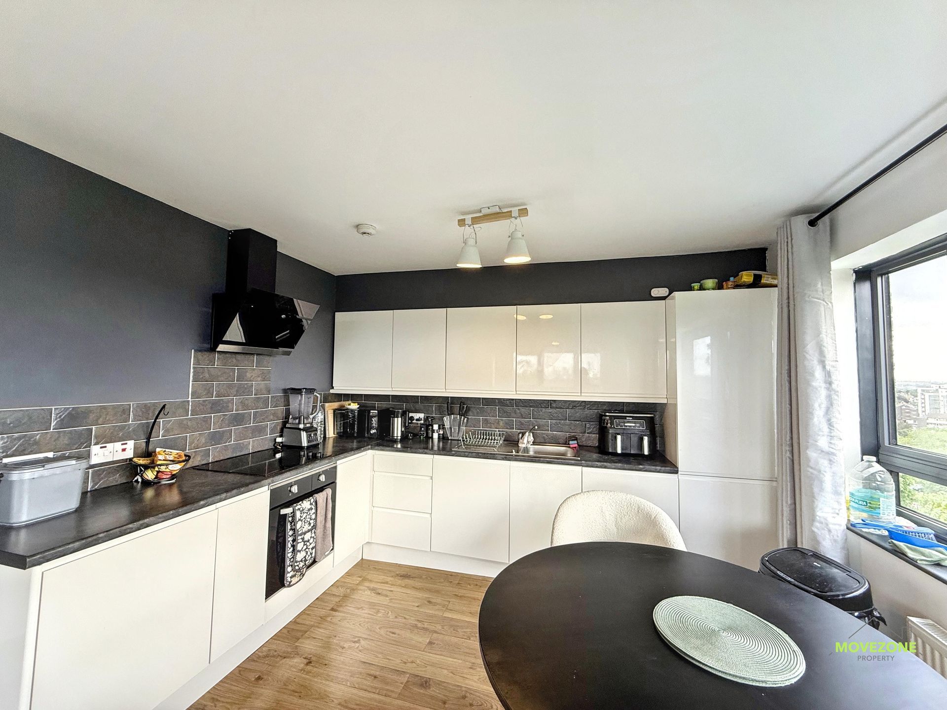 Modern black-and-white kitchen with wood floor, window, and round dining table