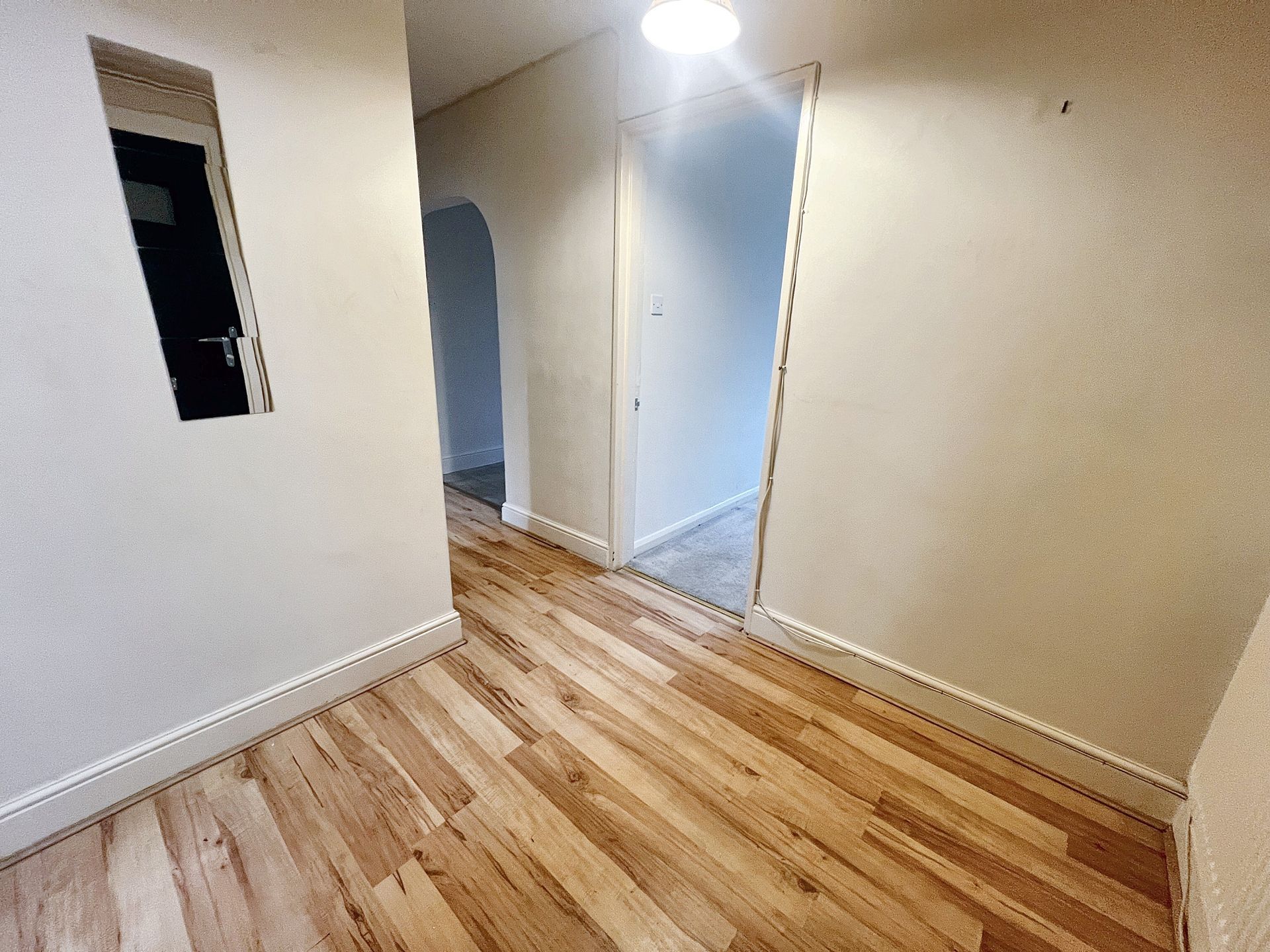 An empty hallway with hardwood floors and white walls.