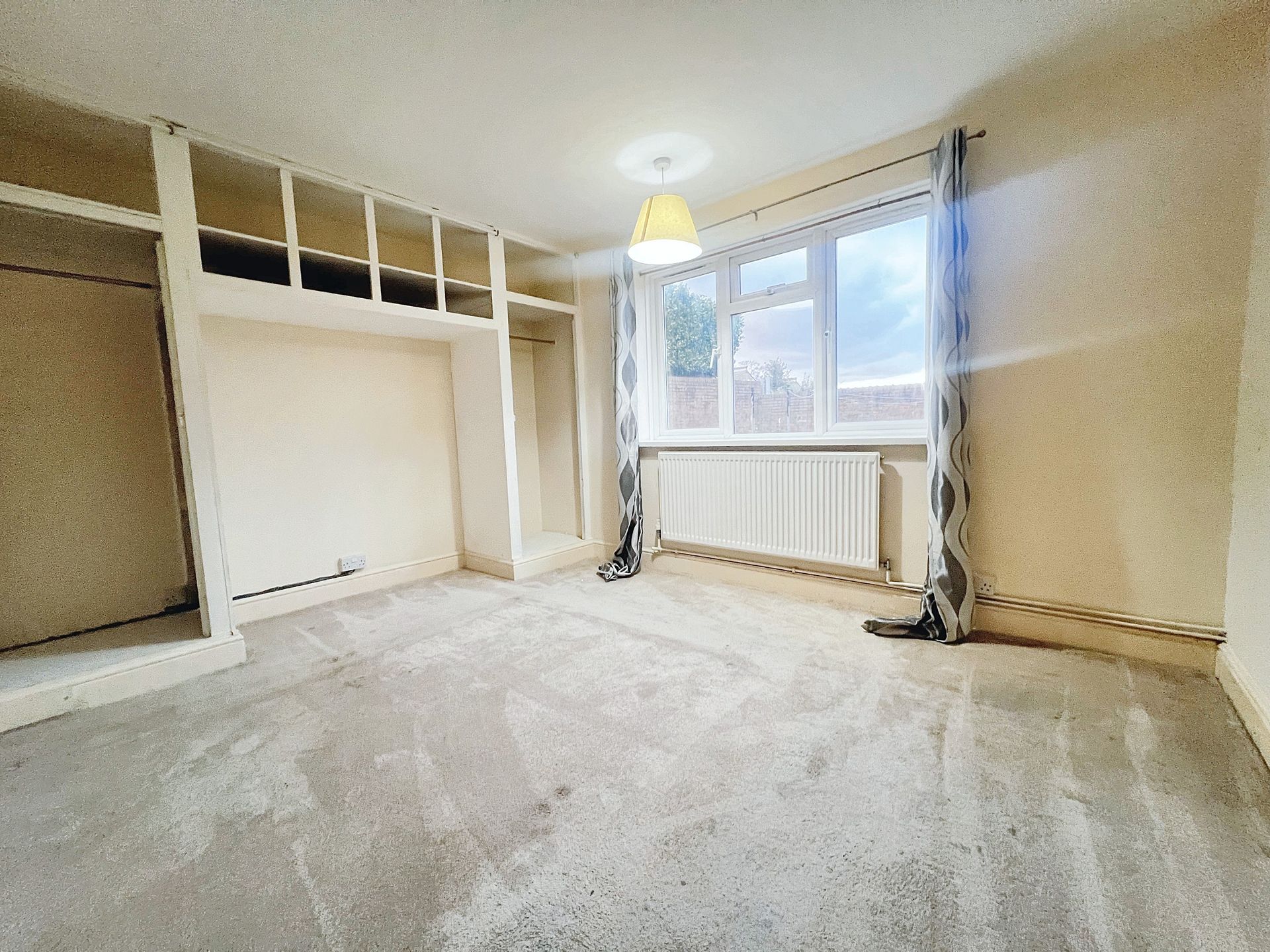An empty room with a large window and a lamp.