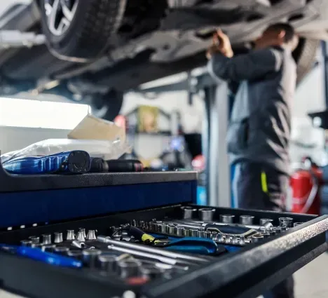 Technician repairing brakes below vehicle | Northside Auto