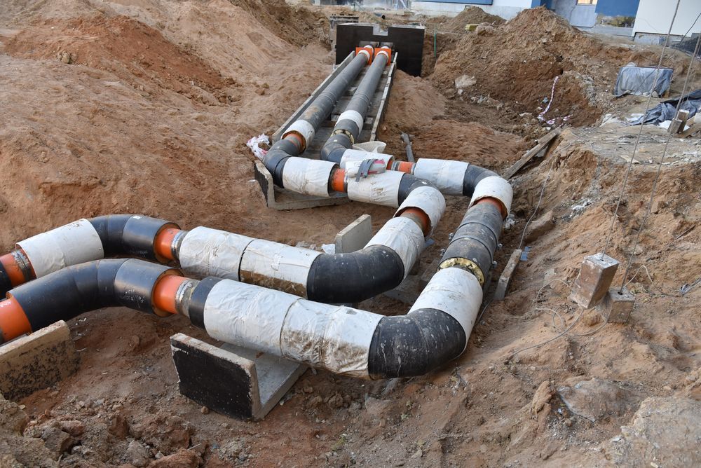 Pipes in a trench, orange and black insulated sections, angled turns, construction site — Gibson Plumbing & Roofing Pty Ltd in Gladstone Central, QLD
