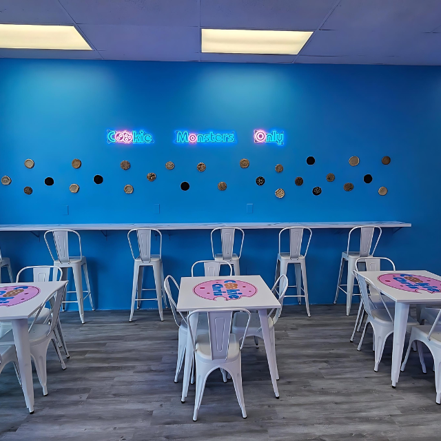 A room with tables and chairs and a blue wall that says kids members only