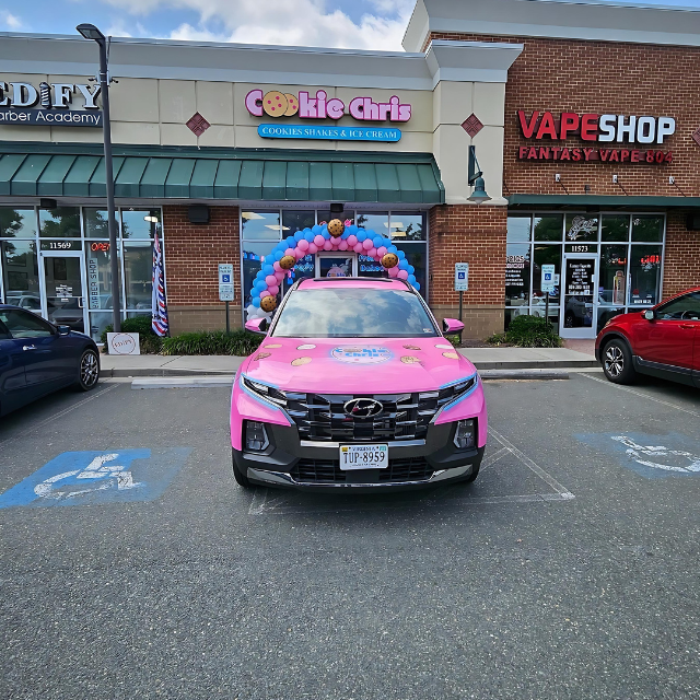 A pink car is parked in front of a vape shop