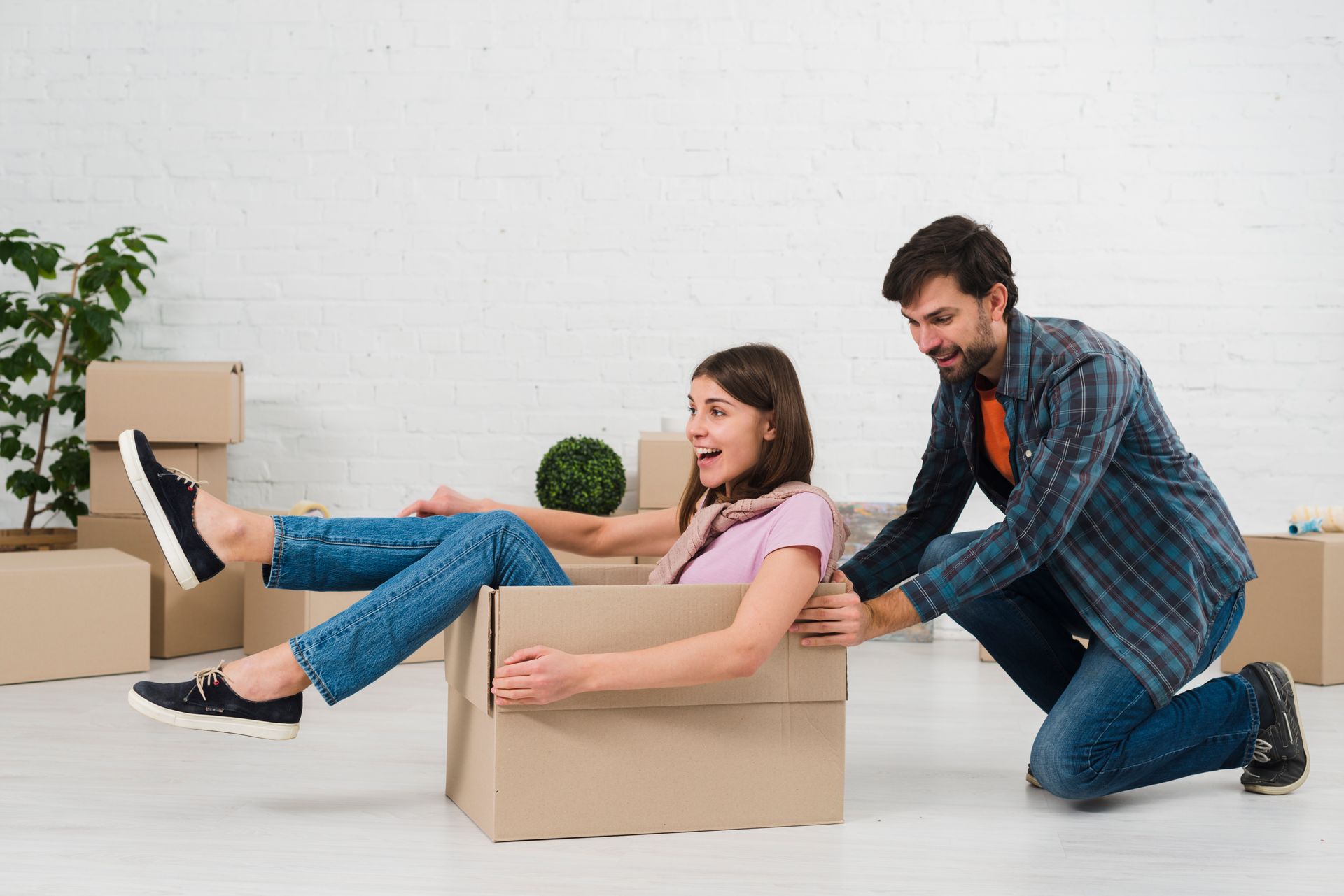 A man is kneeling down next to a woman sitting in a cardboard box.