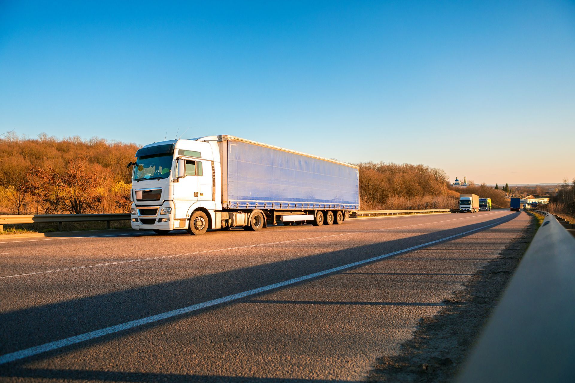 A white truck with a blue trailer is driving down a highway.