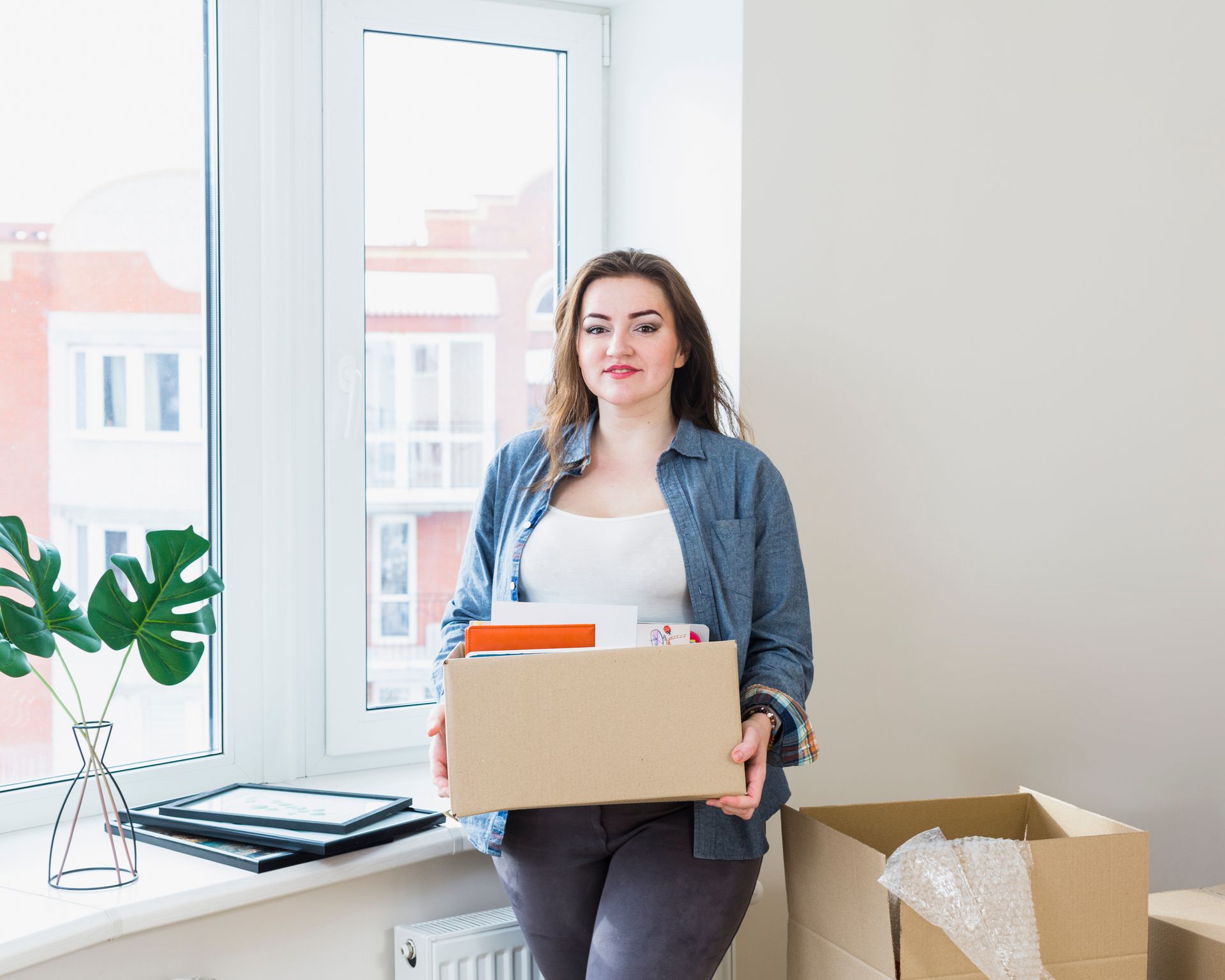 A woman is holding a cardboard box in a room.