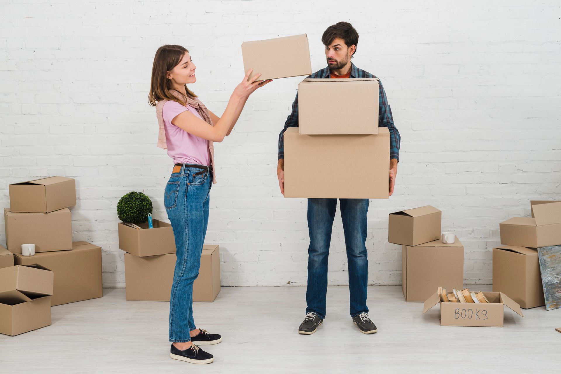A man and a woman are holding cardboard boxes in a room filled with cardboard boxes.