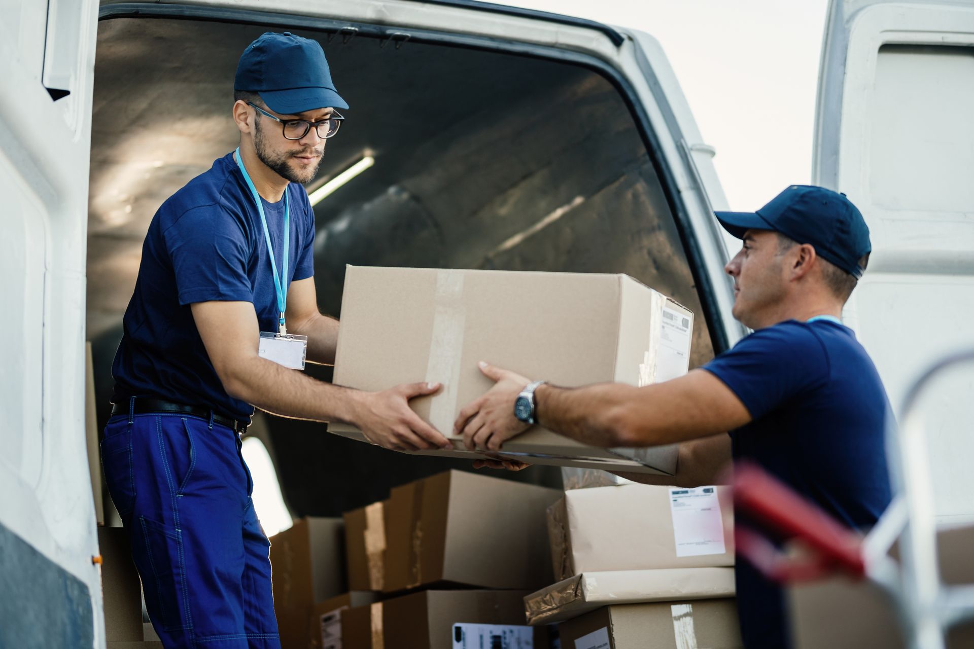 Two delivery men are loading boxes into a van.