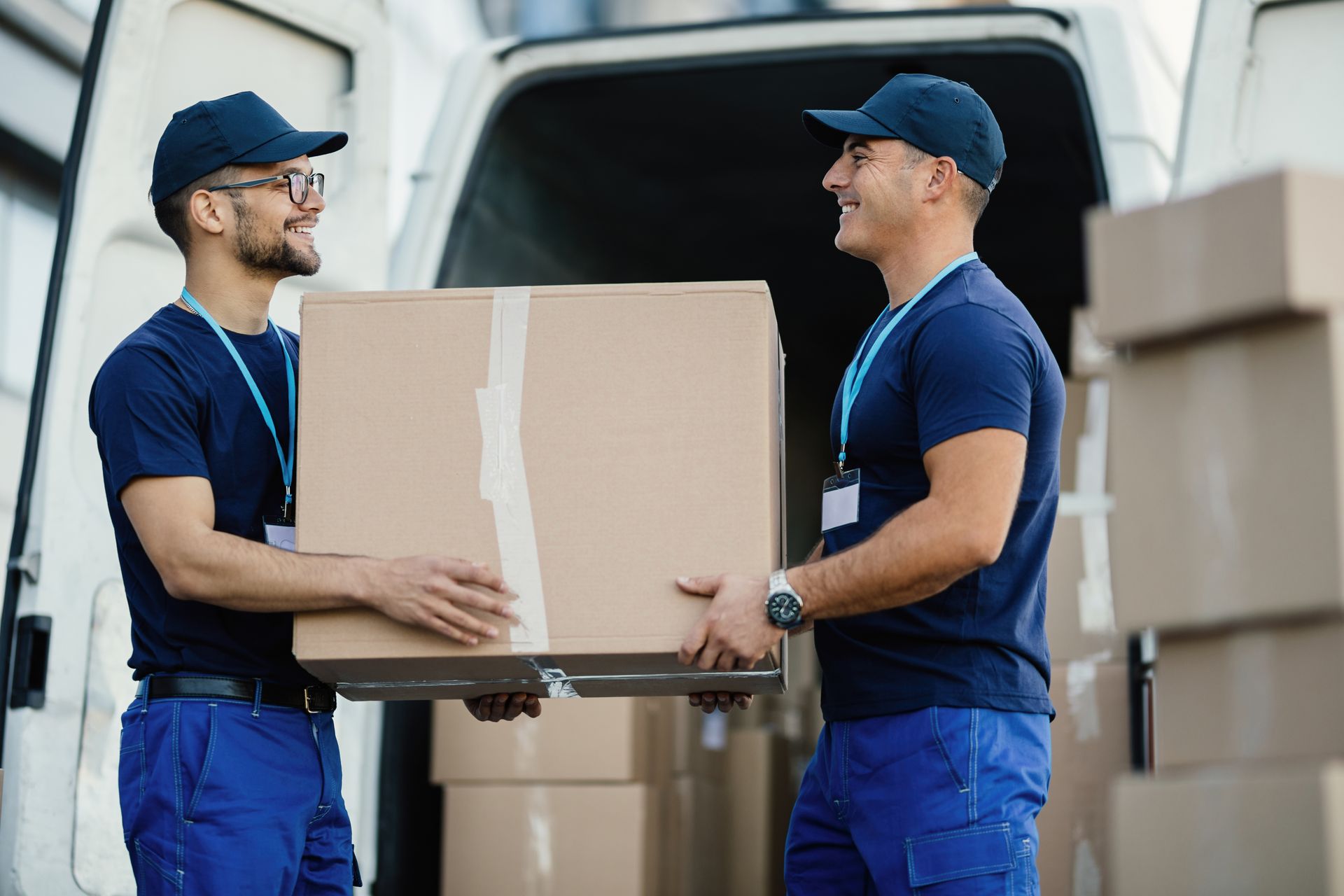 Two delivery men are carrying boxes out of a van.