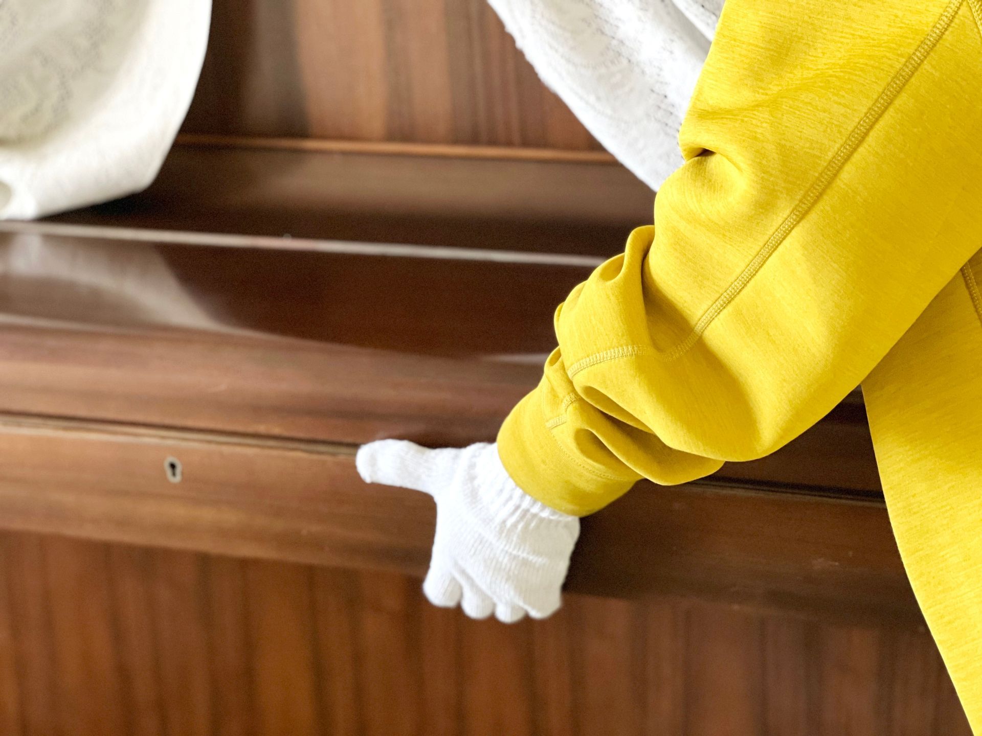 A person wearing a yellow jacket and white gloves is playing a piano