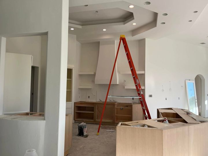 A ladder is sitting in the middle of a kitchen under construction.