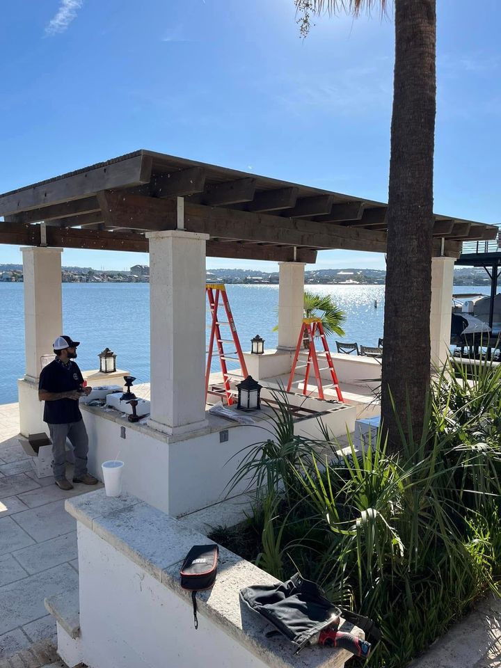 A man is working on a pergola overlooking the water.