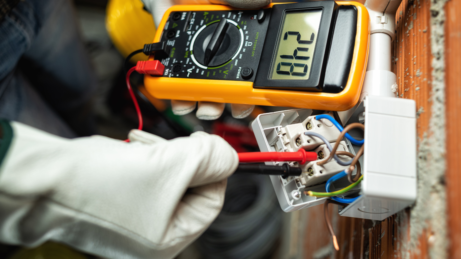 An electrician is using a multimeter to test an electrical outlet.