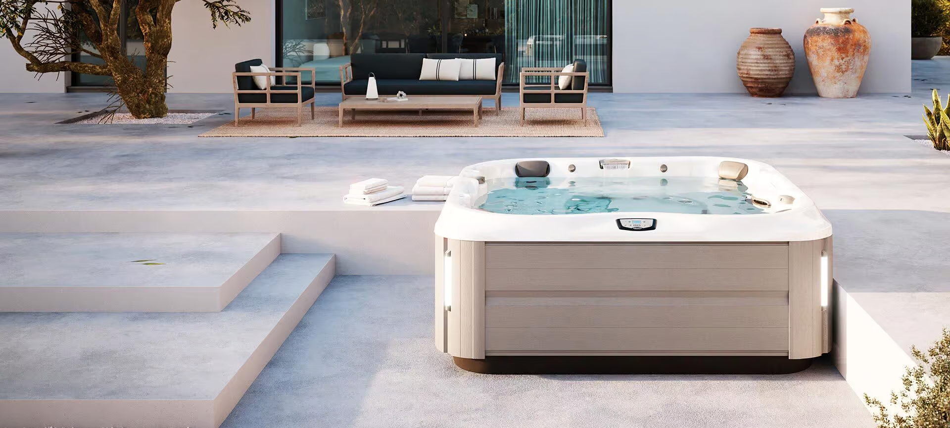 Un bain à remous blanc est installé sur une terrasse devant une maison.