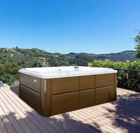 Un spa de nage en bois est posé sur une terrasse en bois.