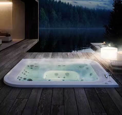 Un jacuzzi est installé sur une terrasse en bois à côté d'un lac.