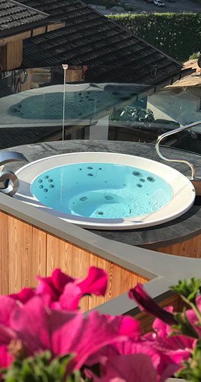 Une terrasse en bois avec un bain à remous et des chaises longues.