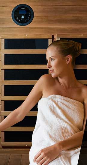 Une femme enveloppée dans une serviette est assise dans un sauna.