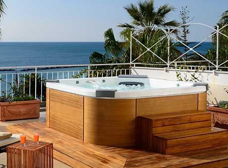 Un bain à remous est installé sur une terrasse en bois surplombant l'océan.