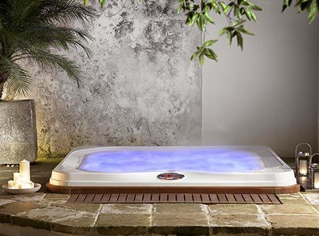 Un jacuzzi est posé sur un sol carrelé à côté d'un palmier.