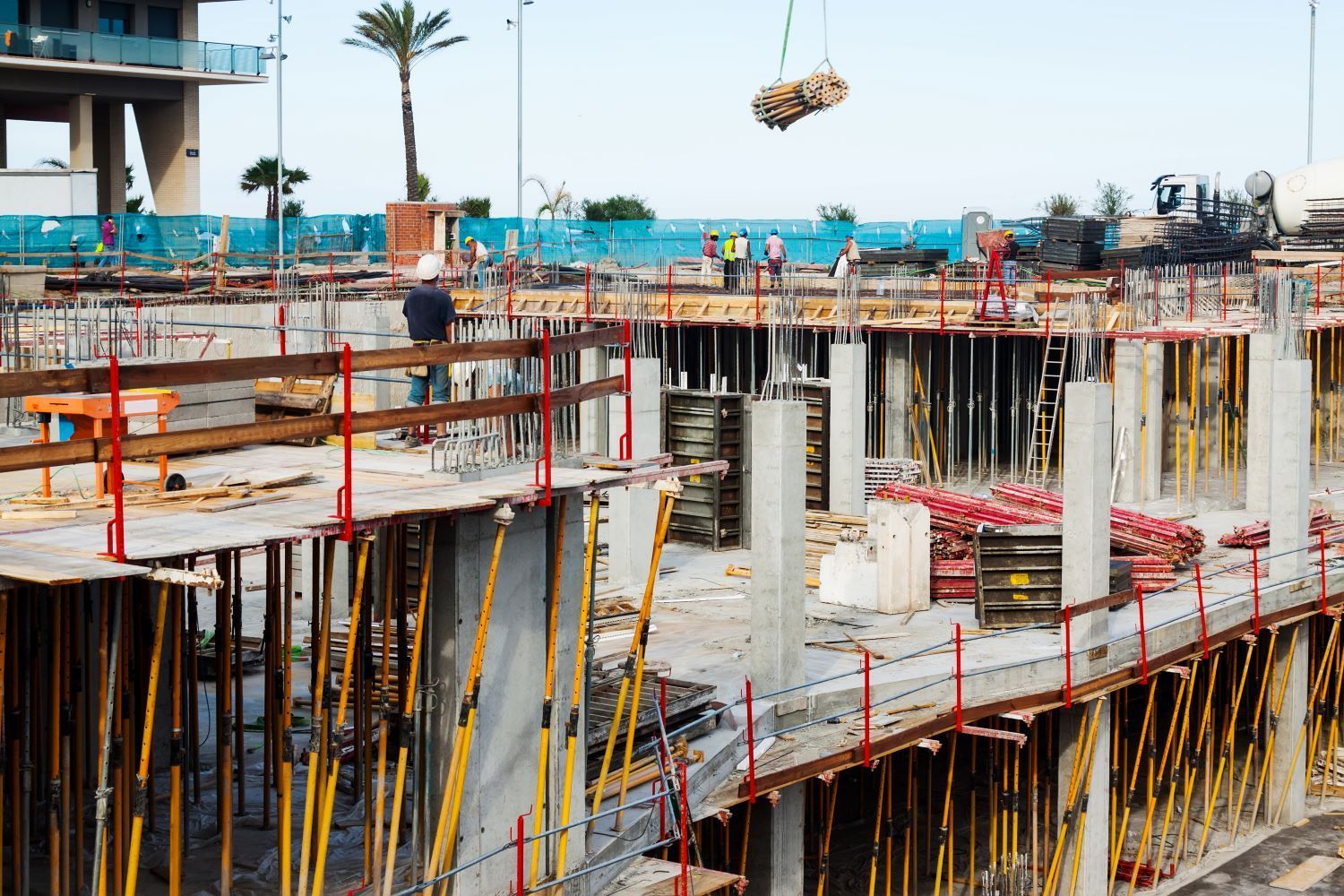 Un sitio de construcción con una grúa levantando una losa de hormigón.