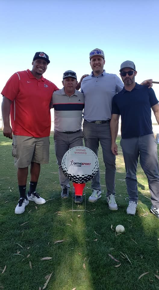 A group of men are posing for a picture on a golf course.