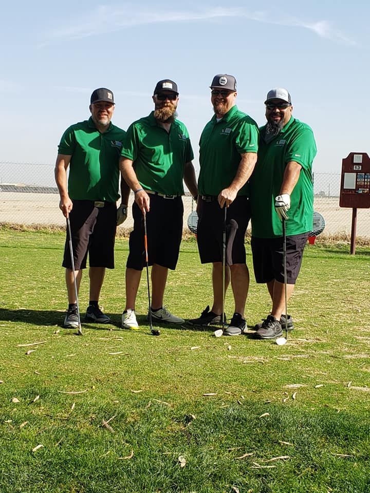 A group of men are standing on a golf course holding golf clubs.