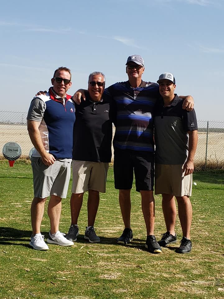 A group of men are posing for a picture on a golf course.