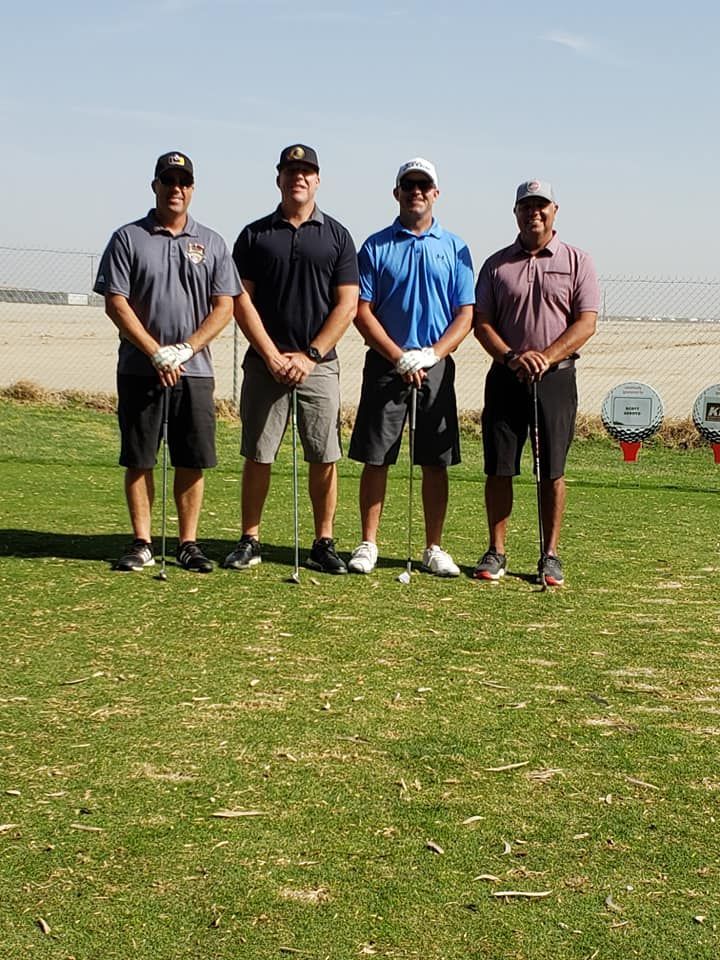 A group of men are standing on a golf course holding golf clubs.
