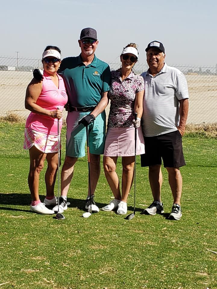 A group of people standing on top of a golf course holding golf clubs.